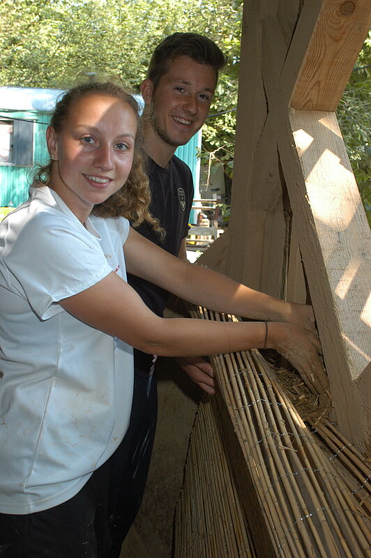 „Wir arbeiten gern mit nachhaltigen Rohstoffen“, meint Architekturstudentin Inga Michelau (21) aus Lübeck. Sie füllt im Pavilloninneren die verlorene Schalung aus Reetmatten mit der Lehm-Reethackschnitzel-Mischung. Hinten: Manuel Horn (21) aus Hambu