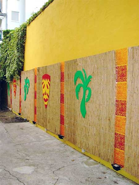 The reed panels were decorated with coloured palm leaves and mask motives. Between the reed panels acrylic netting and spot lights were mounted.